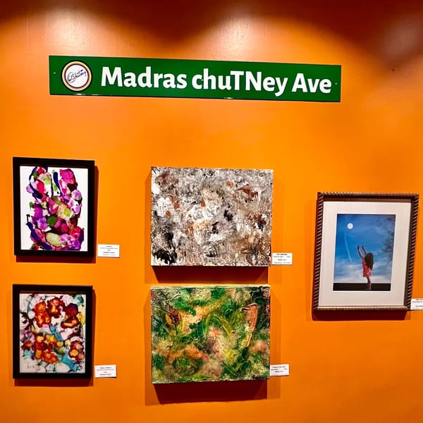 A green "Madras chuTney Ave" sign above five colorful abstract paintings on an orange wall.