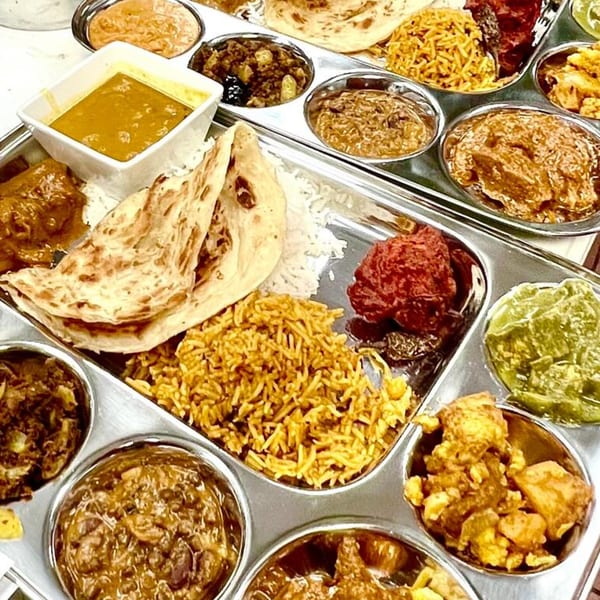 A close-up of an Indian thali with various curries, rice, naan, and chutneys.