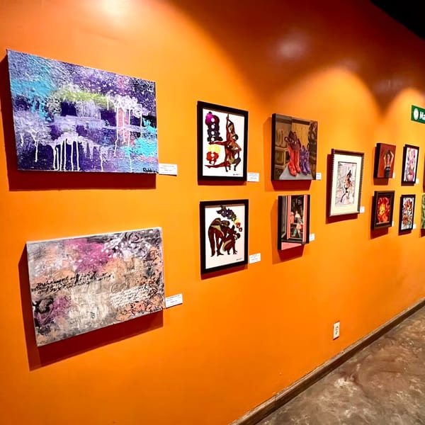 Vibrant orange wall adorned with various framed artworks and abstract paintings, creating a gallery-like ambiance.
