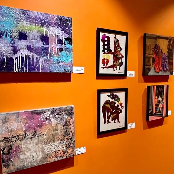 Vibrant orange wall adorned with various framed and unframed abstract and figurative artworks.
