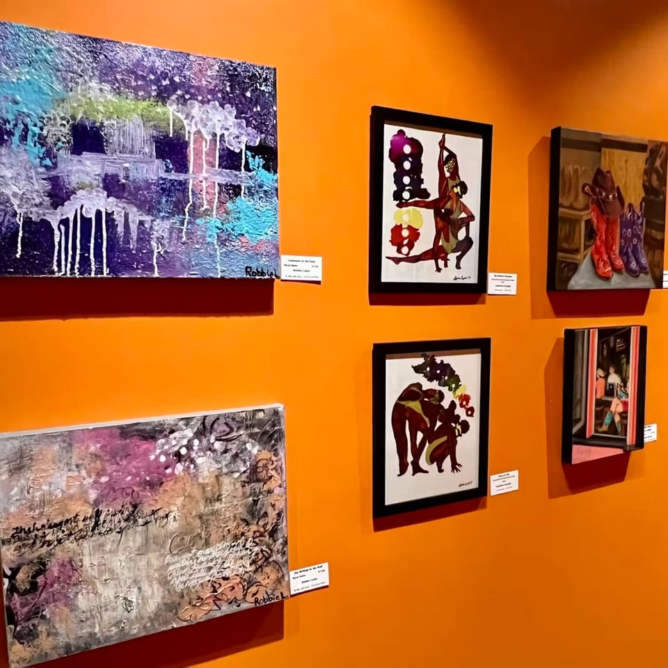 Vibrant orange wall adorned with various framed and unframed abstract and figurative artworks.