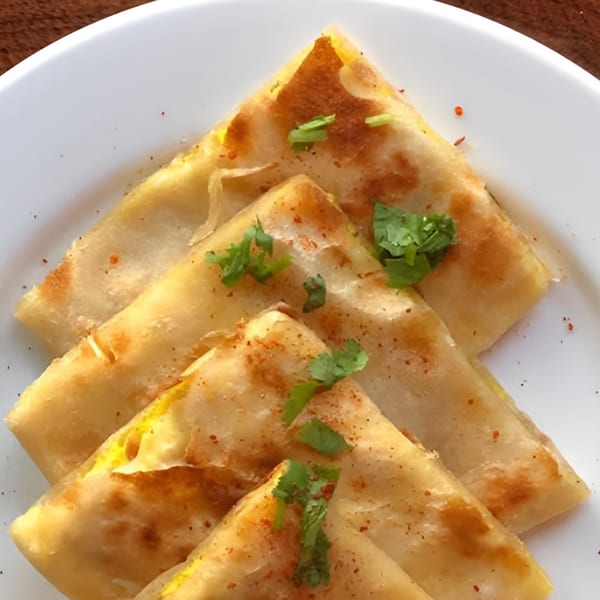Golden brown Indian parathas, garnished with fresh cilantro and spices, on a white plate.