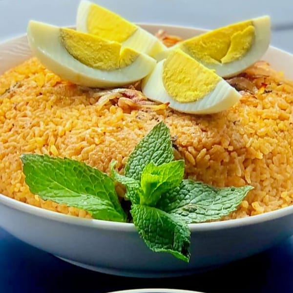 Indian egg biryani with mint leaves and sliced hard-boiled eggs in a white bowl.